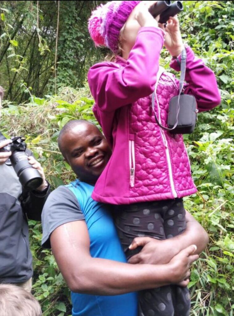 Guide lifting child for birdwatching – Tours in Rwanda